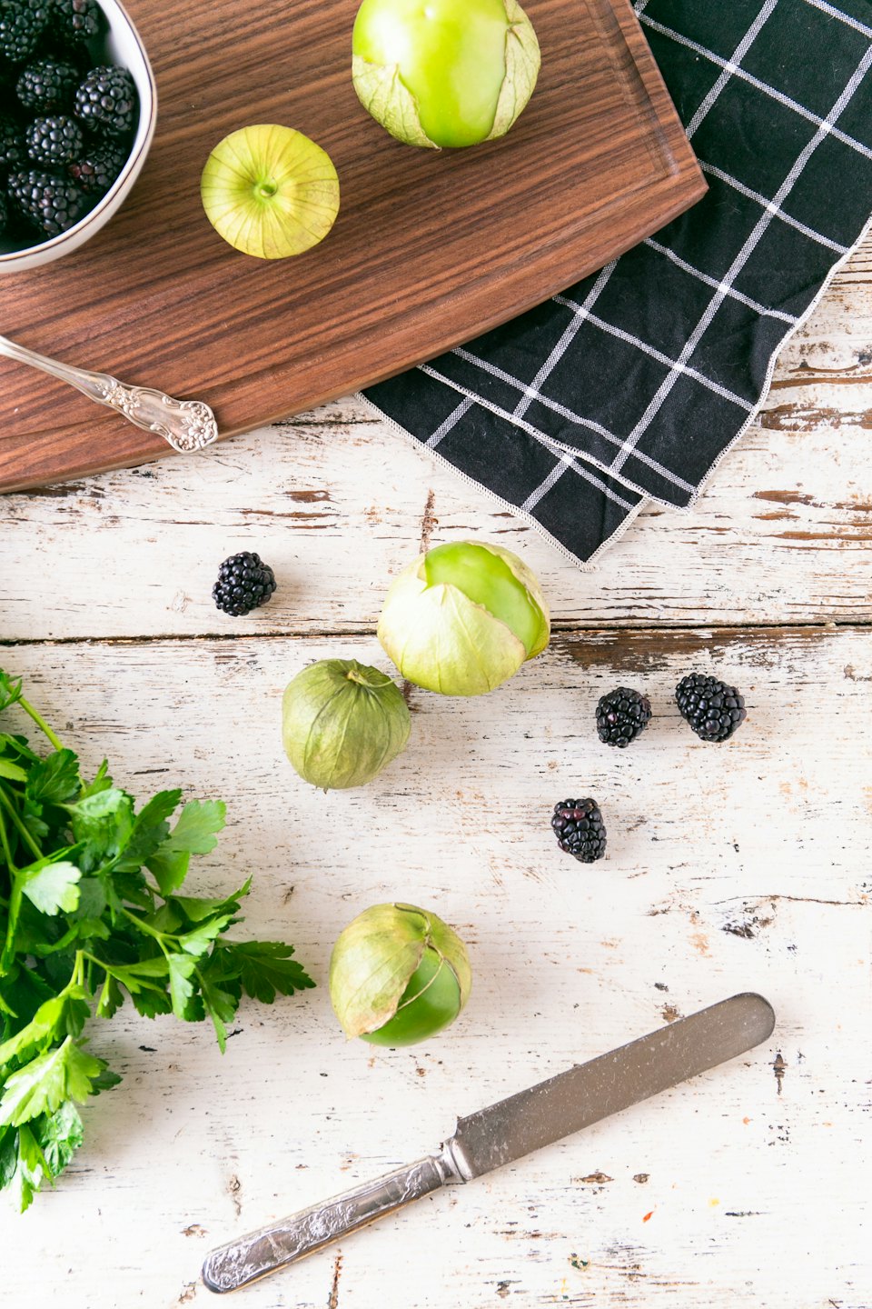 Tomatillos, blackberries, and parsley on a wooden table.